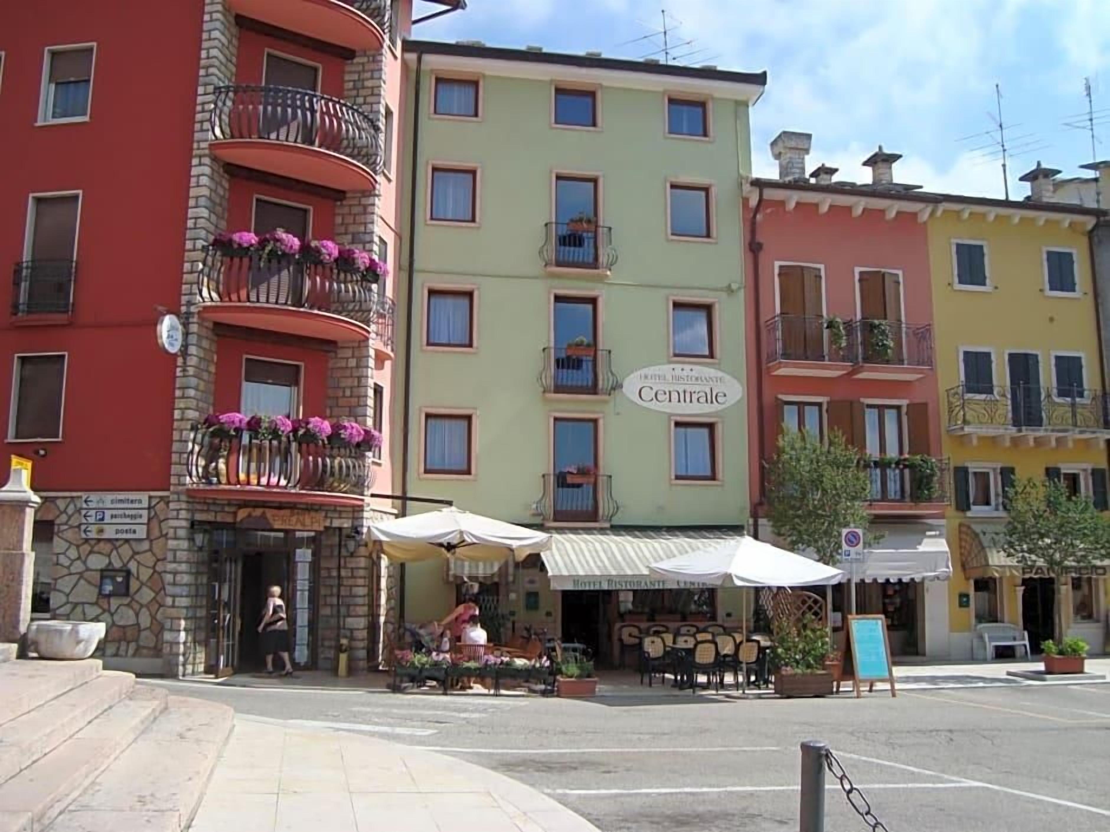 A hotel with a sign 'Hotel Restaurant Centrale' and outdoor seating.
