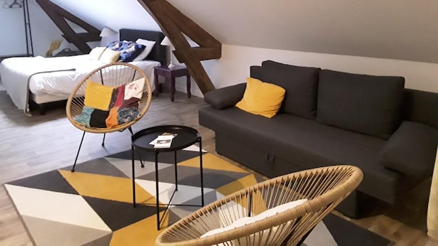 Un espai modern tipus loft amb un llit, un sofà, una cadira i una taula petita.