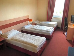 A hotel room with three beds, a desk with a computer, and a window with curtains. - Schleswig Holstein Hotel (Elmshorn)