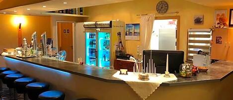 Un coin bar avec des tabourets, un mini-bar et un réfrigérateur.