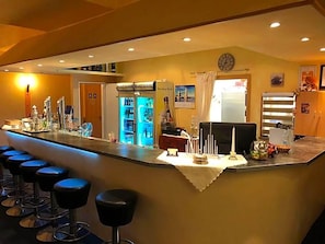 Zona de bar con taburetes, un mini bar y un refrigerador.