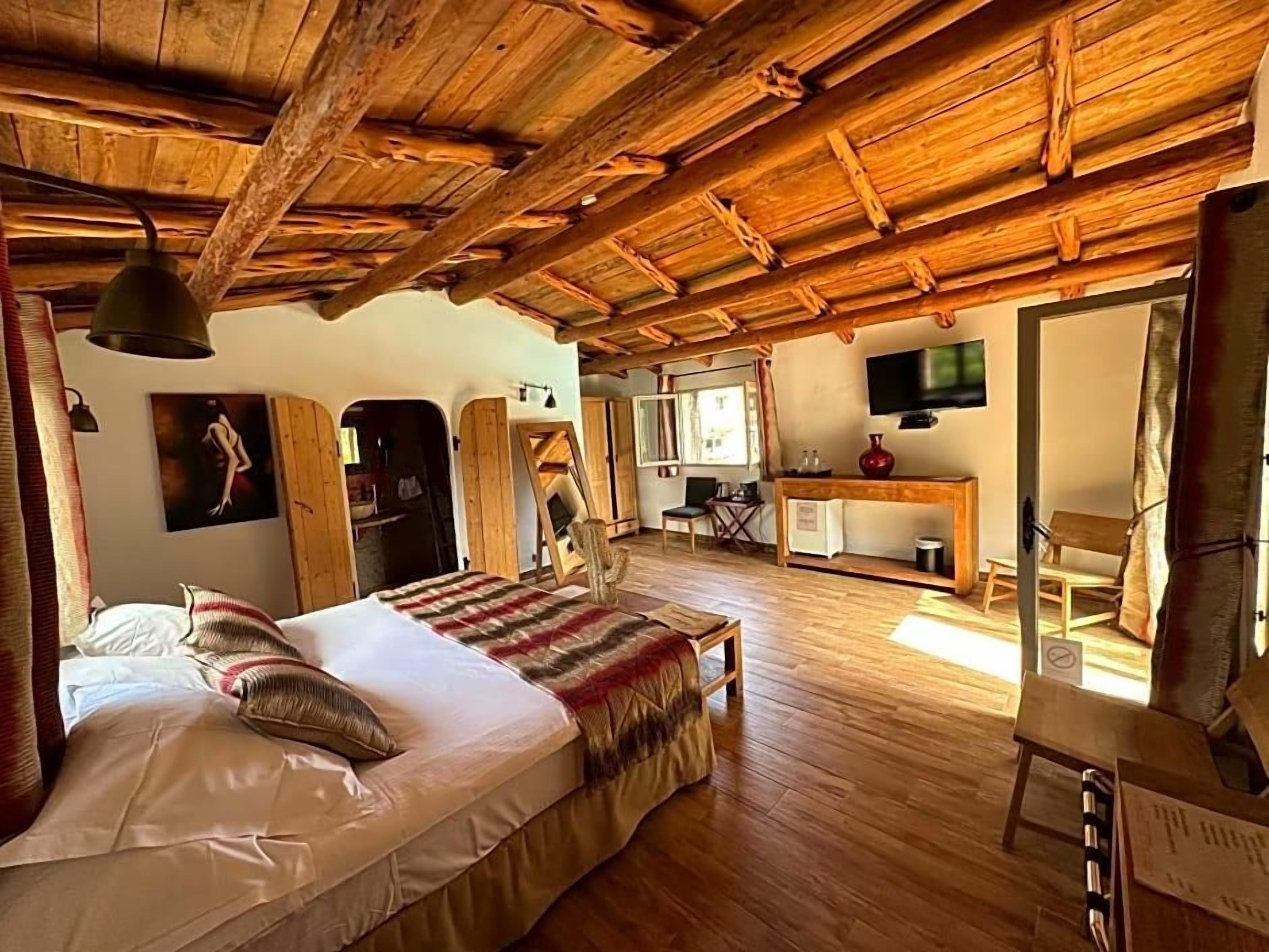 Un intérieur rustique en bois, avec un lit, un bureau et un téléviseur.