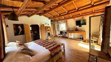 Un intérieur rustique en bois, avec un lit, un bureau et un téléviseur.