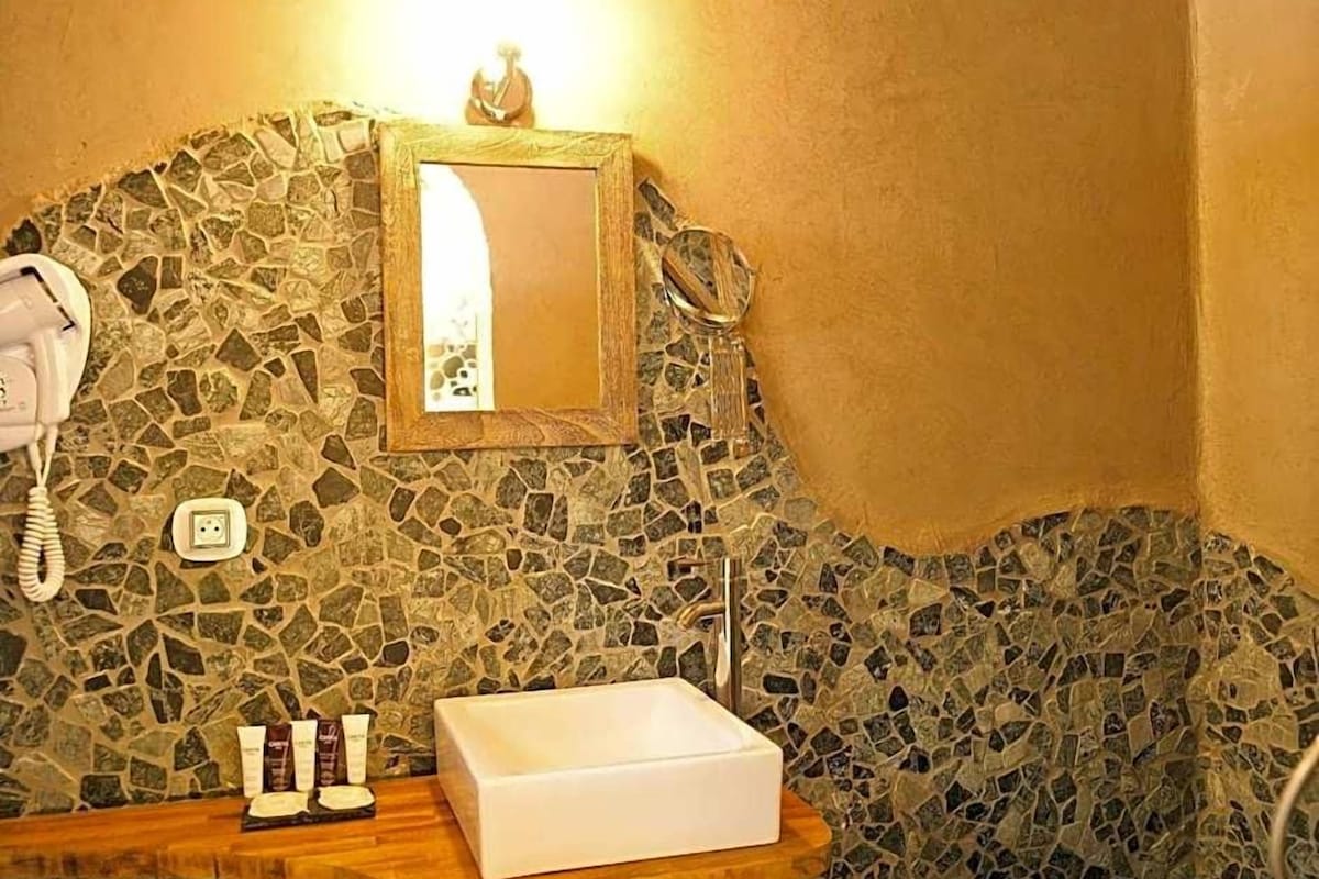 A bathroom with a mosaic wall, a white sink, and a telephone.