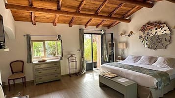 Une chambre à coucher avec un plafond en bois, un lit, une table de chevet, une chaise, une commode et une fenêtre avec des rideaux.