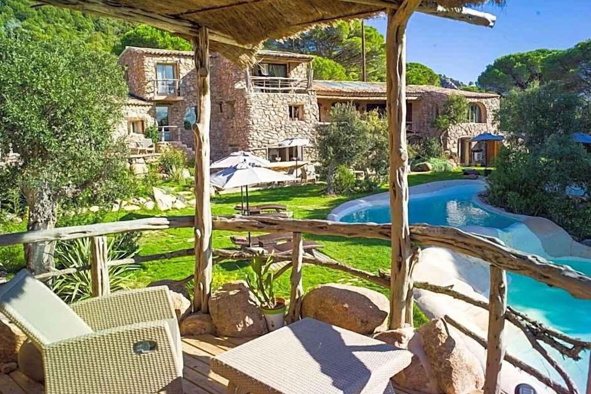 A poolside area with lounge chairs, a stone building, and a clear blue pool.