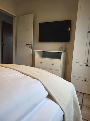 A bedroom with a bed, a television mounted on the wall, and a wardrobe. - Weltmann S Hotel Restaurant (Ennepetal)