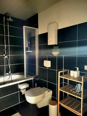 A modern bathroom with a bathtub, toilet, and a shower area. - Weltmann S Hotel Restaurant (Ennepetal)
