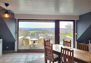 A room with a dining table and chairs, a view through a glass door, and a hanging light fixture. - Weltmann S Hotel Restaurant (Ennepetal)