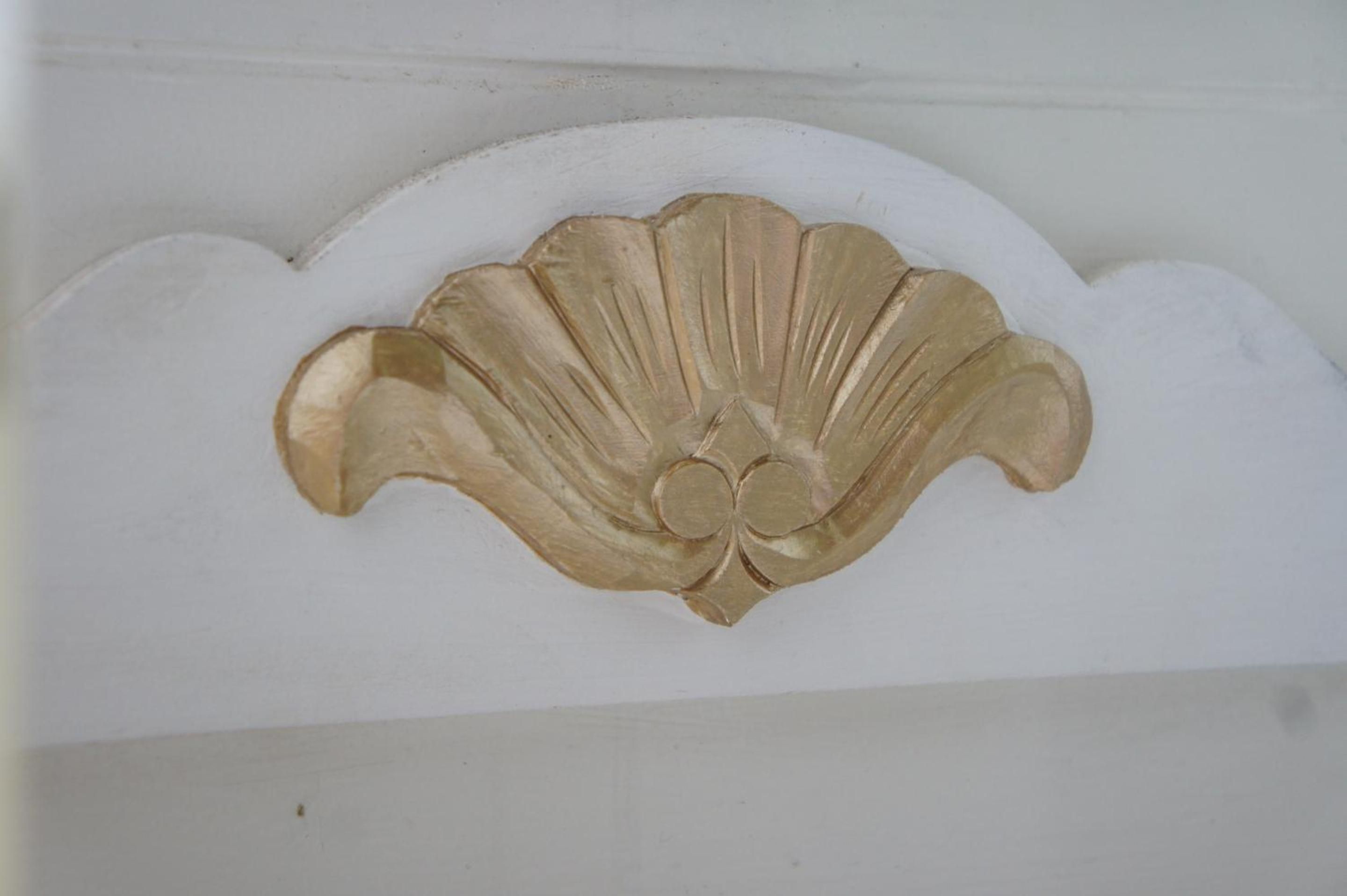 Un motivo decorativo de concha sobre una pared blanca.