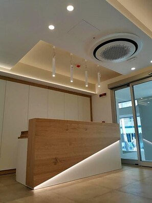Un comptoir d’accueil avec un revêtement en bois et un luminaire moderne placé au-dessus.