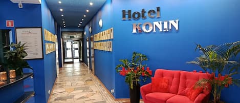 Zona de recepción de hotel con pared azul, un sofá rojo y un techo con diseño de estrellas.