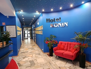 A hotel reception area with a blue wall, a red sofa, and a ceiling with a starry design.
