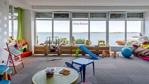 A children's play area with a view of the sea, featuring play equipment and seating.