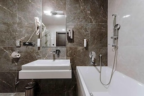 A modern bathroom with a white sink, a bathtub, and a shower. - Hotel Glamour (Kaluža)