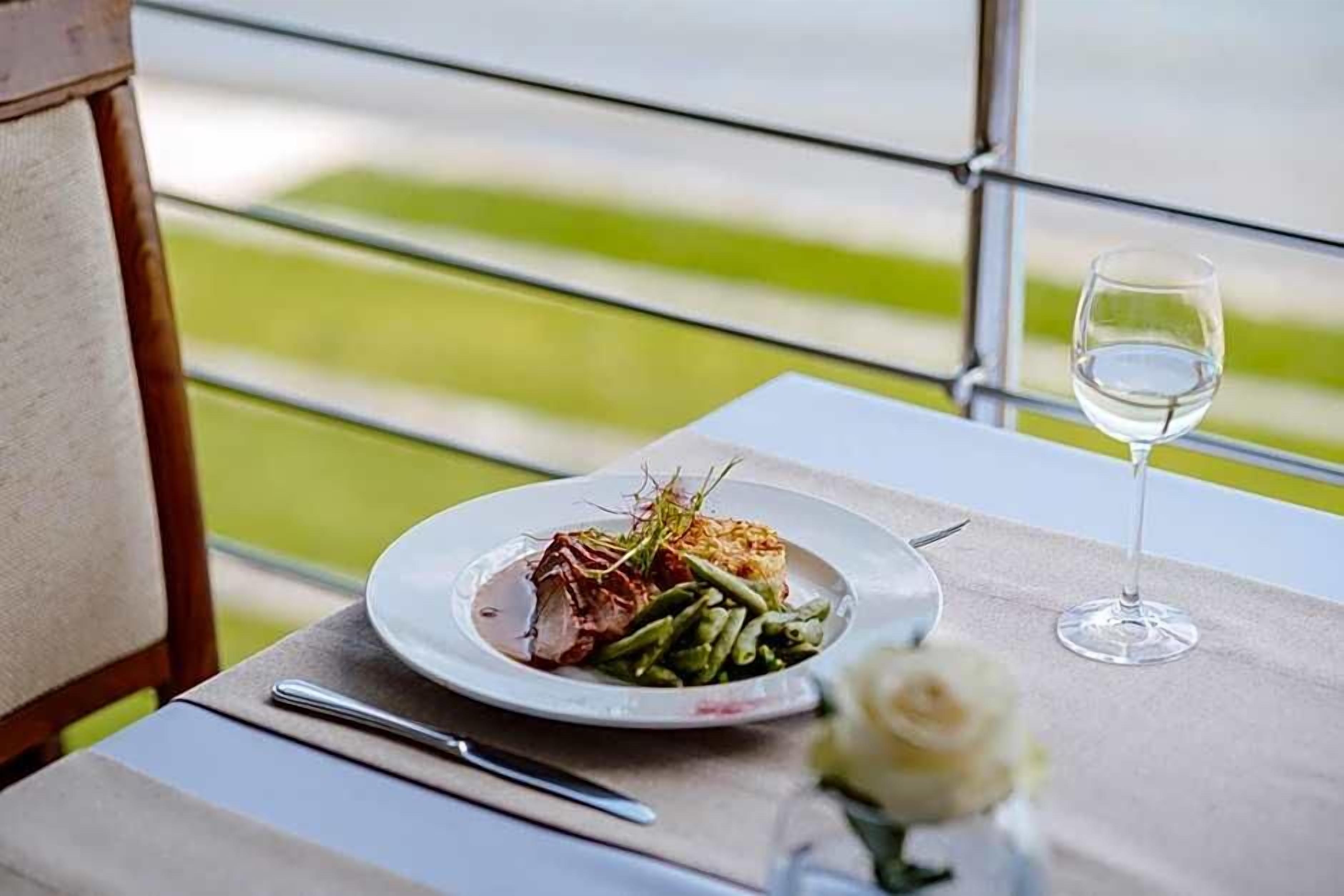 A dining table with a plate of food, a wine glass, and a fork.
