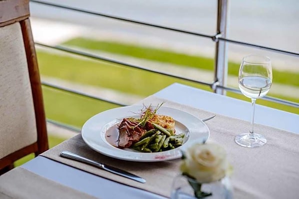 A dining table with a plate of food, a wine glass, and a fork.