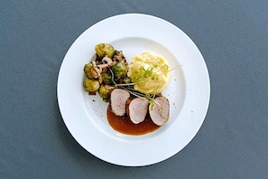 A plate with sliced meat, mashed potatoes, and Brussels sprouts.