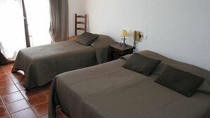 Duas camas de solteiro com cabeceiras, uma mesa de cabeceira com abajur e uma cadeira.