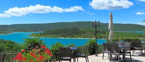 An outdoor seating area with a view of a lake and hills.