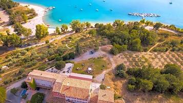 Vue aérienne d’une propriété située sur la côte, avec une plage, des bateaux et un quai.