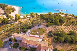 An aerial view of a coastal property with a beach, boats, and a dock. - Auberge Des Salles (Les Salles-sur-Verdon)