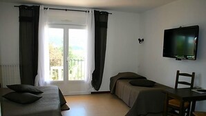 Quarto com duas camas, televisão, mesa e cadeira.