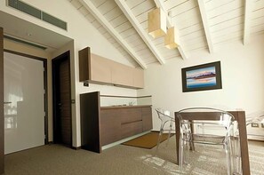 A modern kitchen with a built-in oven, a dining area with a clear glass table, and a framed picture on the wall.