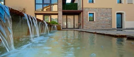 Un bâtiment moderne avec un élément décoratif aquatique à l’avant.