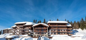 Una cabaña de madera de varios pisos con balcones, rodeada de árboles cubiertos de nieve.