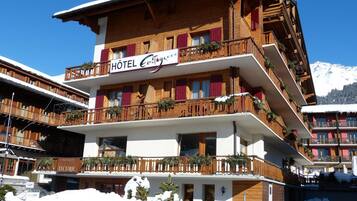 A multi-story hotel with balconies, wooden facade, and a sign indicating it is a restaurant.