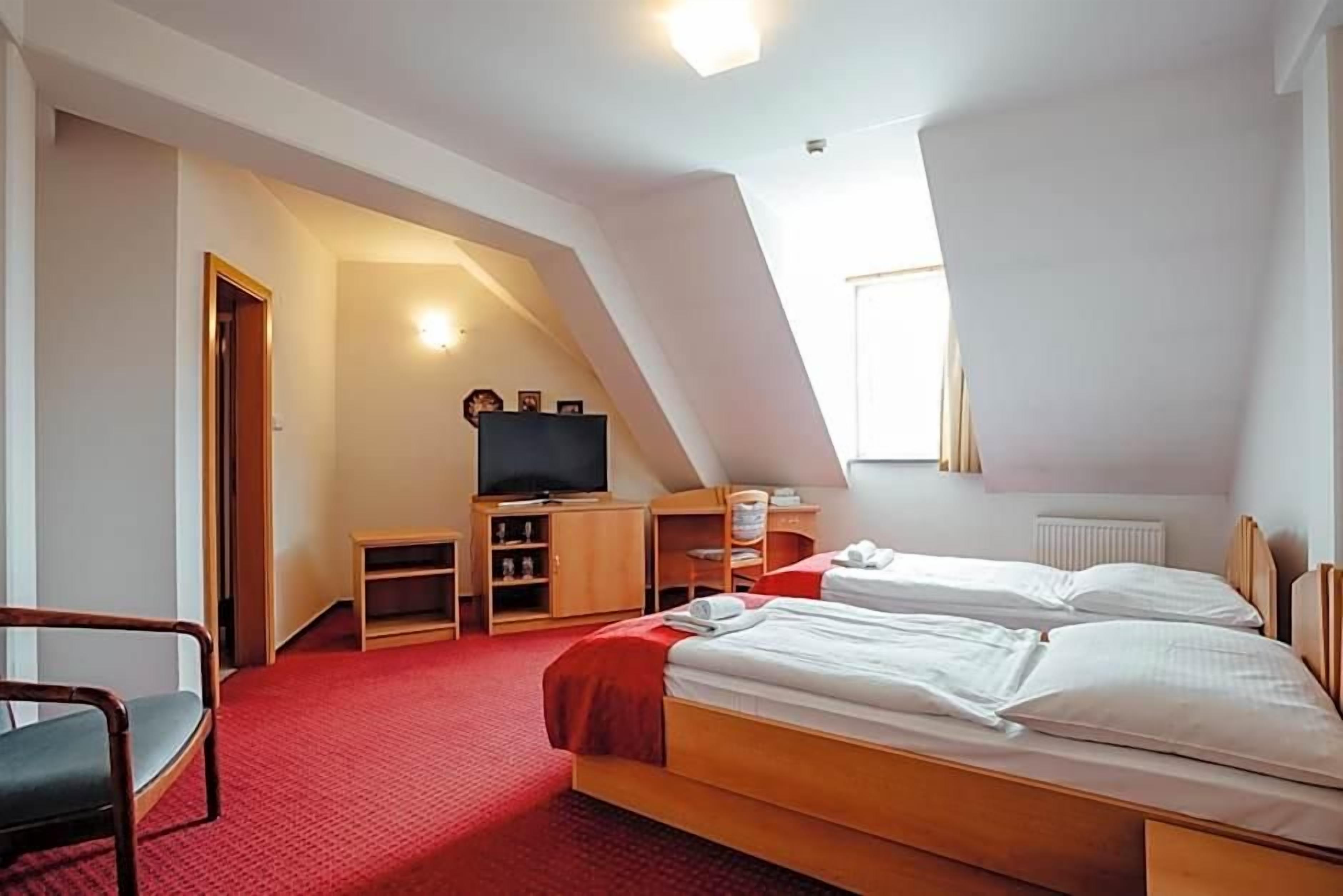 A room with two beds, a television, and a small desk.