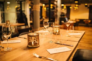 A restaurant table set with wine glasses, cutlery, and candle holders.