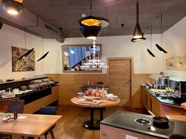 Interior de restaurante con una mesa redonda central, un mostrador de buffet y una zona de cocina.