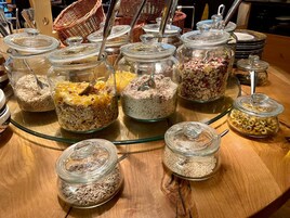 A buffet table with various food items in glass containers, including cereals and granola.