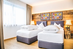 Una habitación de hotel con dos camas, un cabecero de madera y dos lámparas de pared.