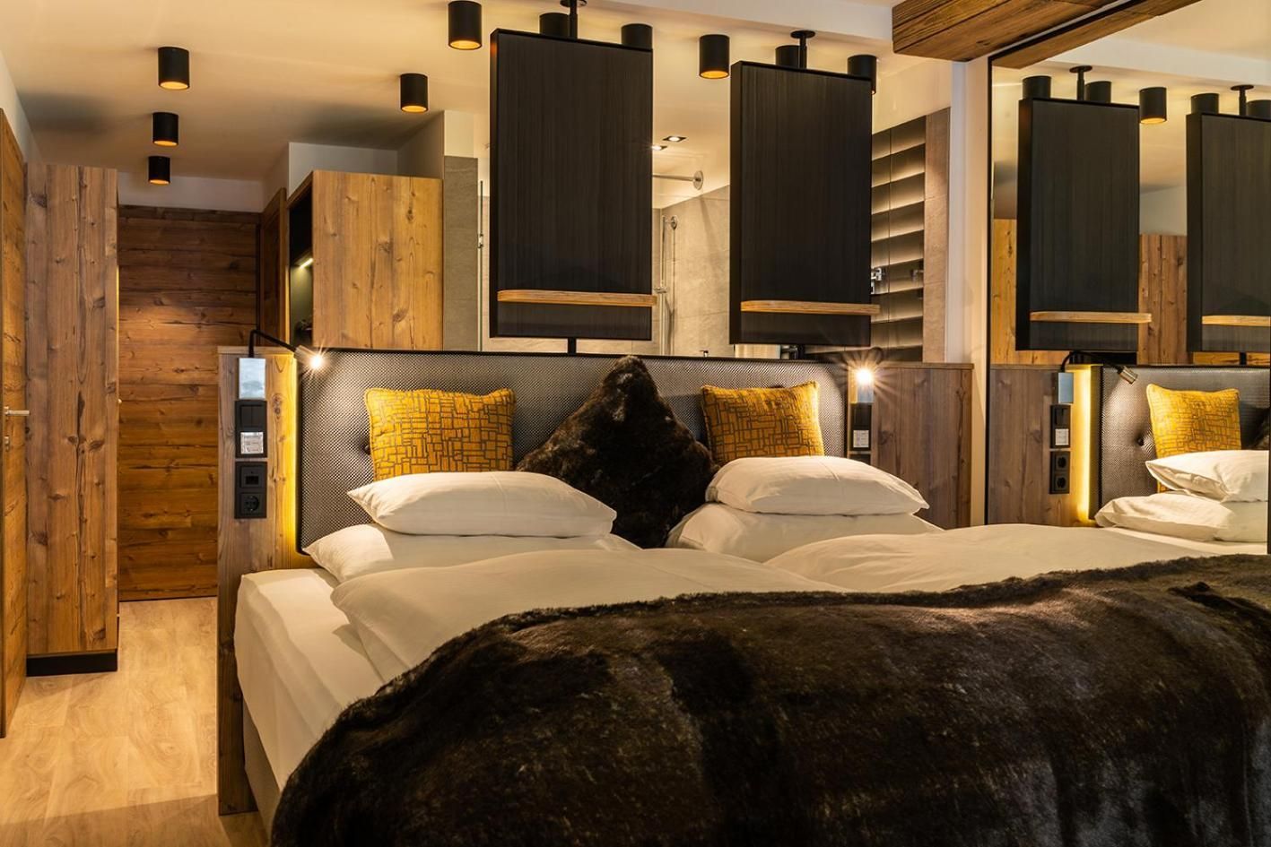 A modern bedroom with a large bed, wooden headboard, and built-in shelving.