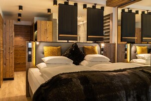 A modern bedroom with a large bed, wooden headboard, and built-in shelving.