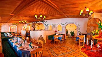 A restaurant with wooden ceiling, multiple tables, and chairs.