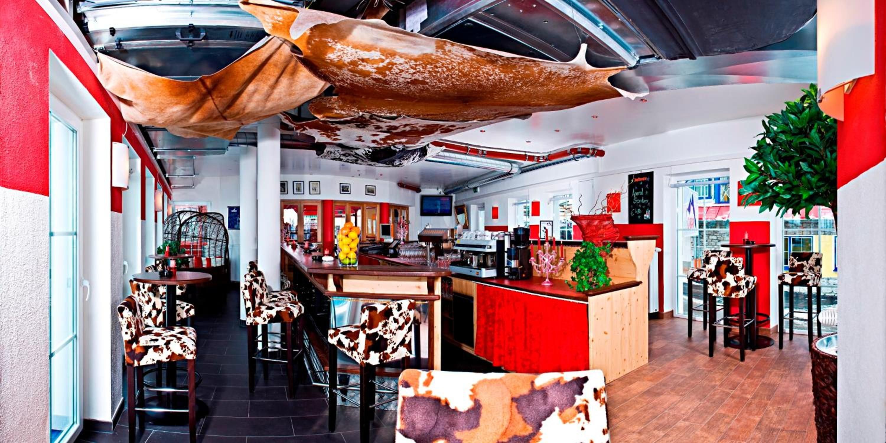 A restaurant interior with high ceilings, a bar area, and cow-print chairs.