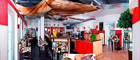 A restaurant interior with high ceilings, a bar area, and cow-print chairs.