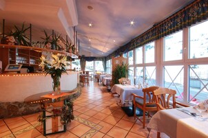 A restaurant with a bar area, tables set for dining, and large windows offering a view.