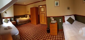 A hotel room with two beds, a wardrobe, a desk with a chair, a trash bin, and a small table with a coffee maker. - Clachaig Inn (Ballachulish)