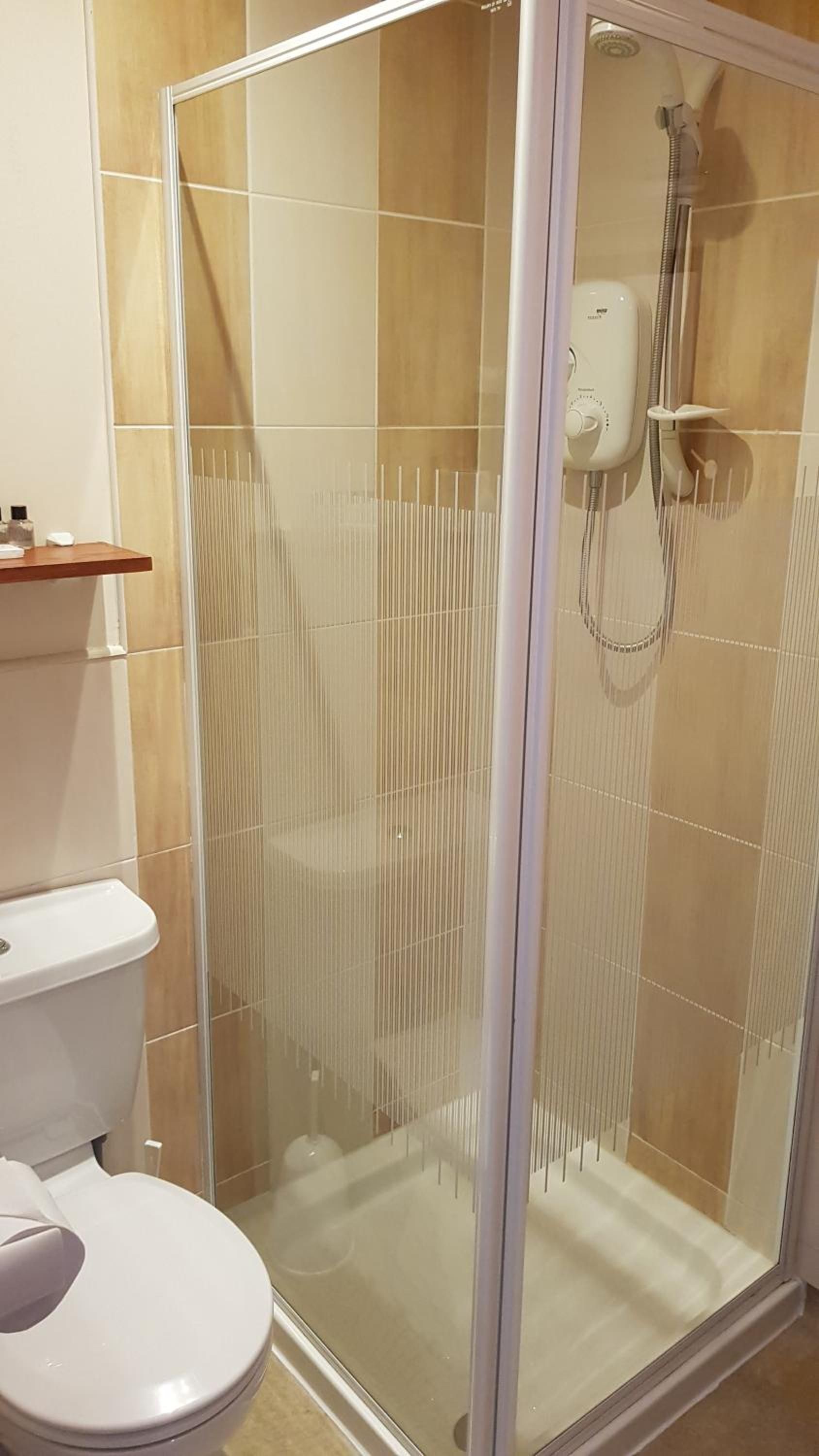 A shower enclosure with a glass door and a handheld showerhead.