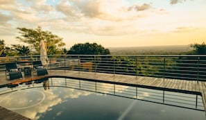Un espace piscine doté d’une terrasse en bois, de chaises longues et offrant une vue sur le paysage.