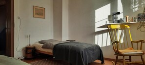 A bedroom with a bed, a chair, a desk with a computer, and a window. - Pilgerhüsli Backpacker (Stafa)