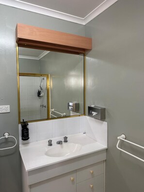 A bathroom with a white sink, a mirror with a gold frame, and a towel rack.