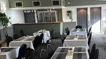 A restaurant with multiple tables, chairs, and a bar area.