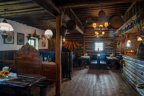 A rustic wooden interior with a long dining table, benches, and hanging light fixtures. - Gosciniec Oycowizna (Lesznowola)