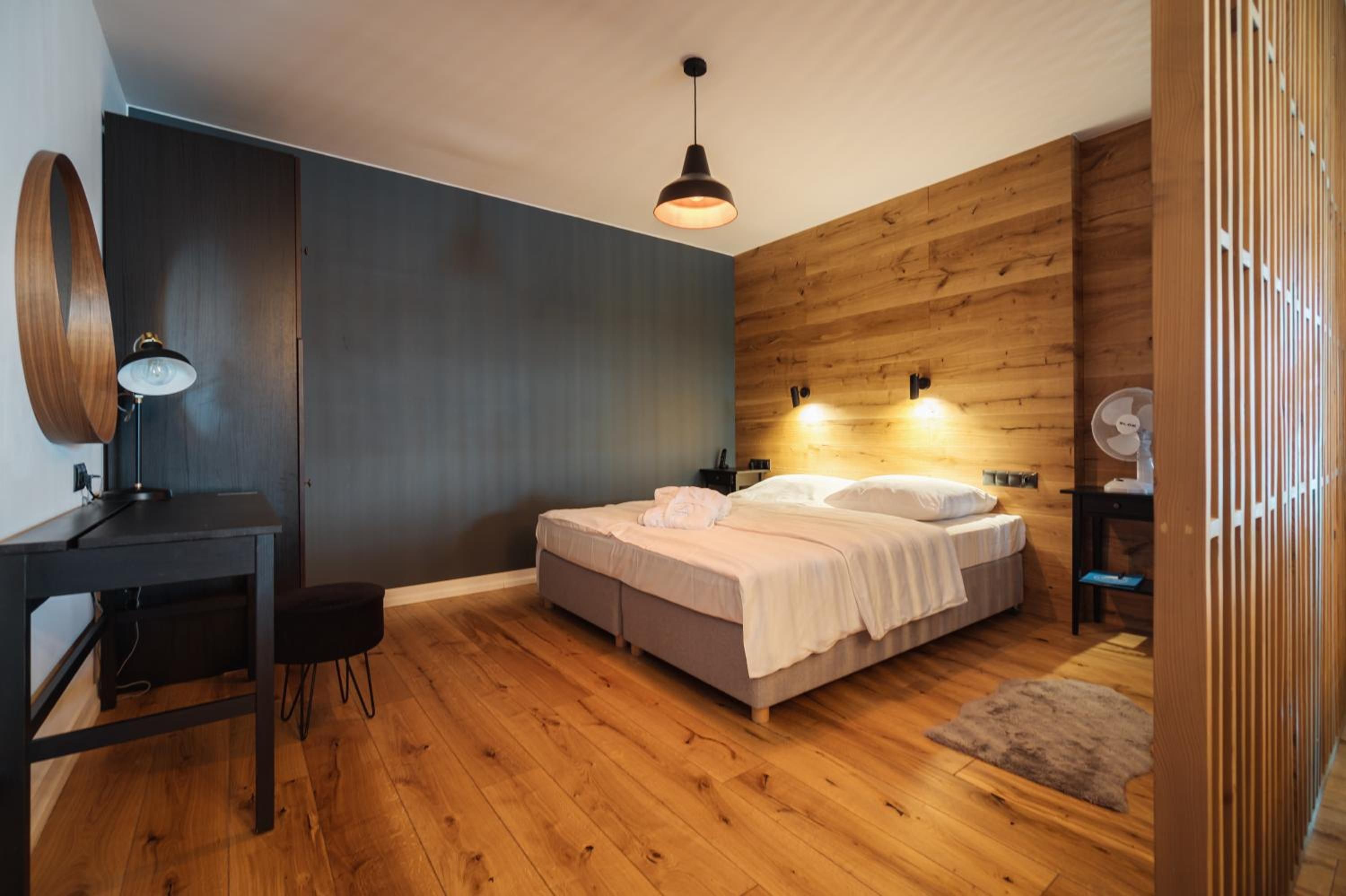 A modern bedroom with a bed, bedside tables, a desk, and a chair.